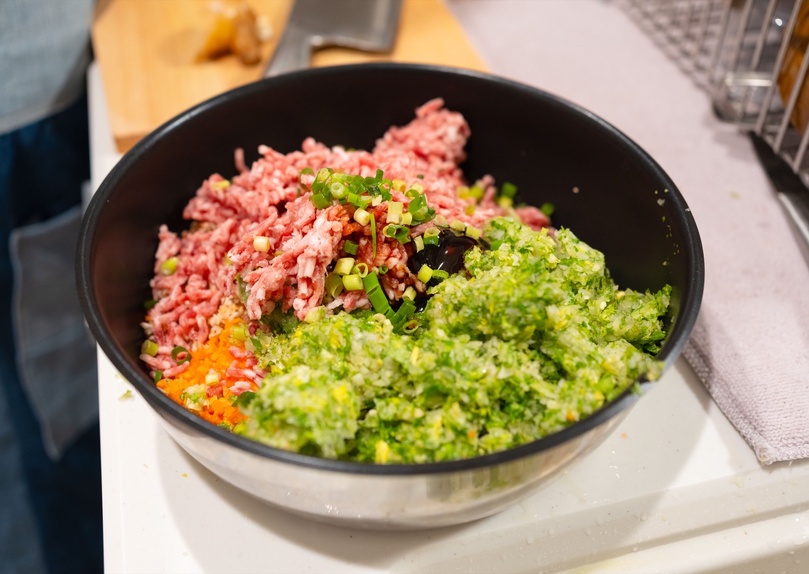 Viande fraîchement hachée et légumes émincés réunis dans un grand bol de préparation