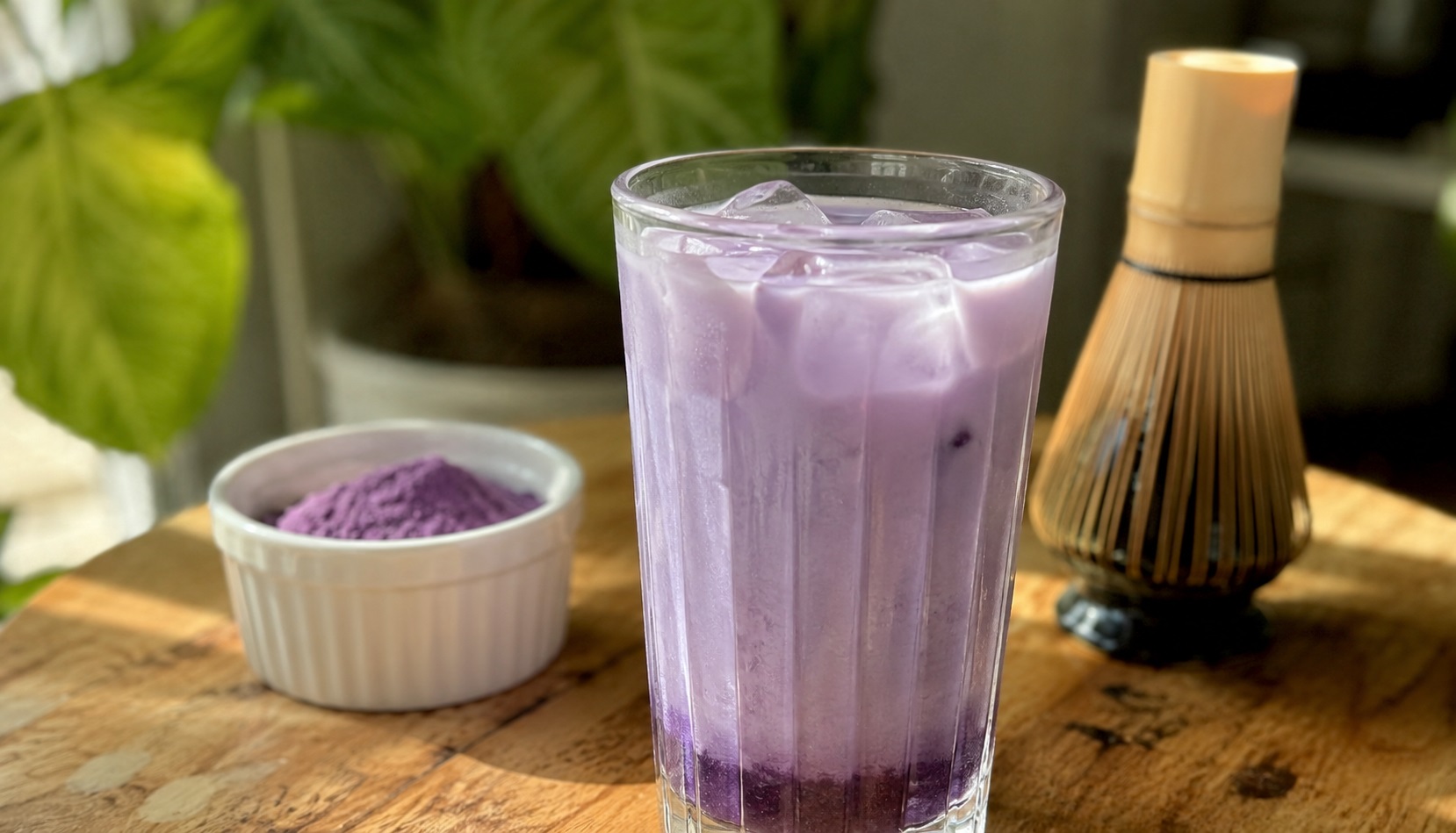 Un ube latte violet servi dans une tasse transparente avec une mousse de lait onctueuse